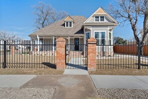 A two-story house with a covered porch, brick pillars, and a gated driveway. - Gloria Estate- 2 blocks to Silos (Waco)