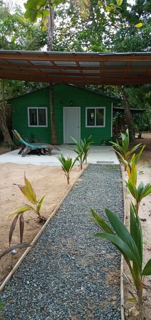 A green house with a gravel pathway leading to it, surrounded by tropical vegetation. - Incredible Loft on the Beach! (Bocas del Toro)