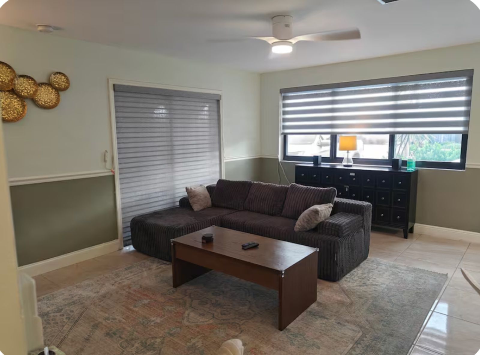 A living room with a sofa, coffee table, and a window with blinds.