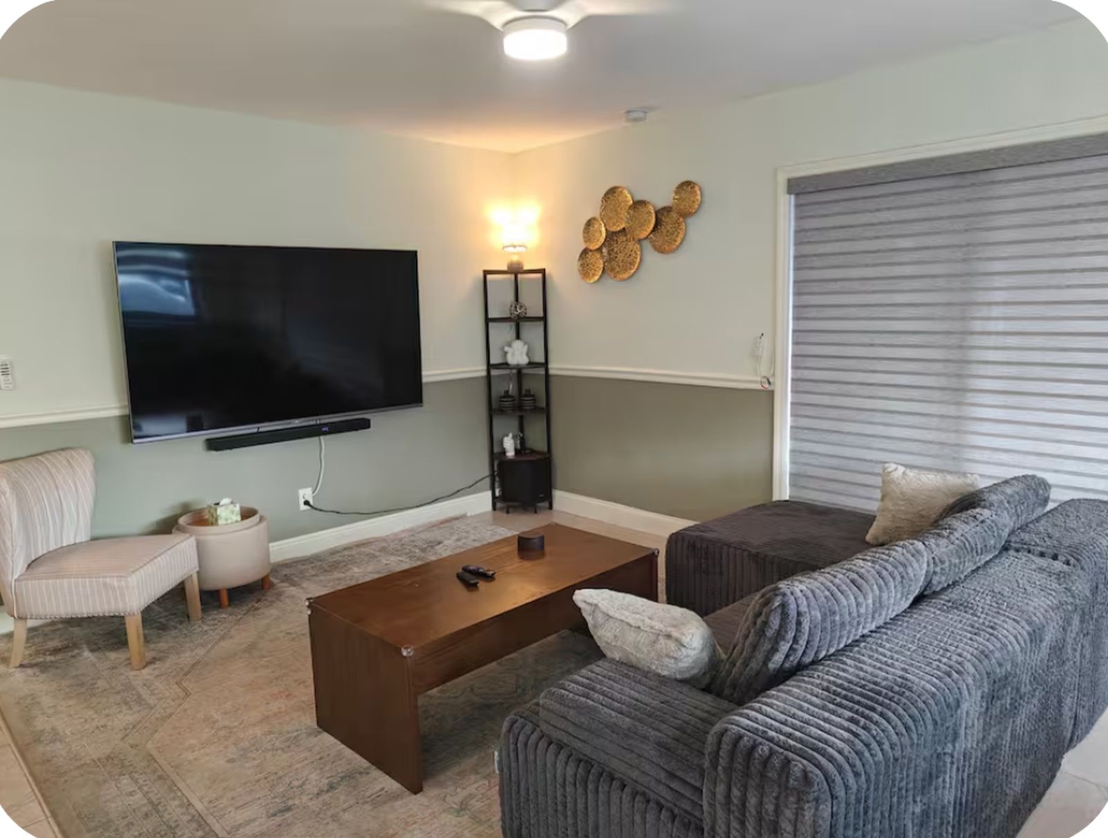 Una sala de estar con una televisión de pantalla plana, una mesa de centro, un sofá, una mesita auxiliar y una lámpara.