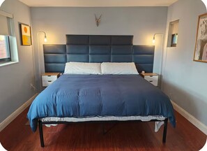 A bedroom with a large bed, two bedside tables, a headboard, and wall-mounted lamps. - 2 Bedroom Suite ~ 1 block from Wilton Drive ~ Fenced backyard (Wilton Manors)