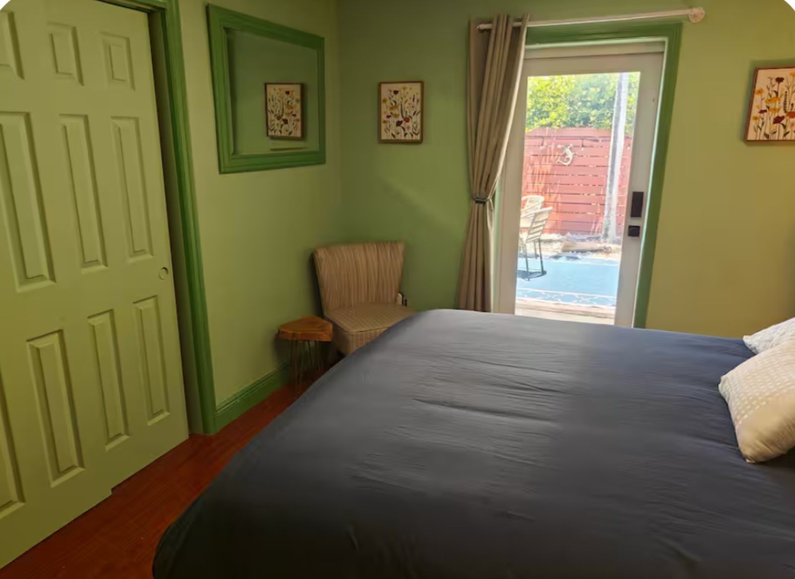Una habitación con cama, una silla, una puerta y vistas al exterior.
