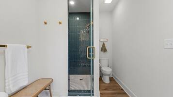 A bathroom with a shower, toilet, and bench.