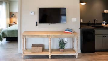 A modern living room with a wooden console table, a mounted flat-screen TV, and a small potted plant.