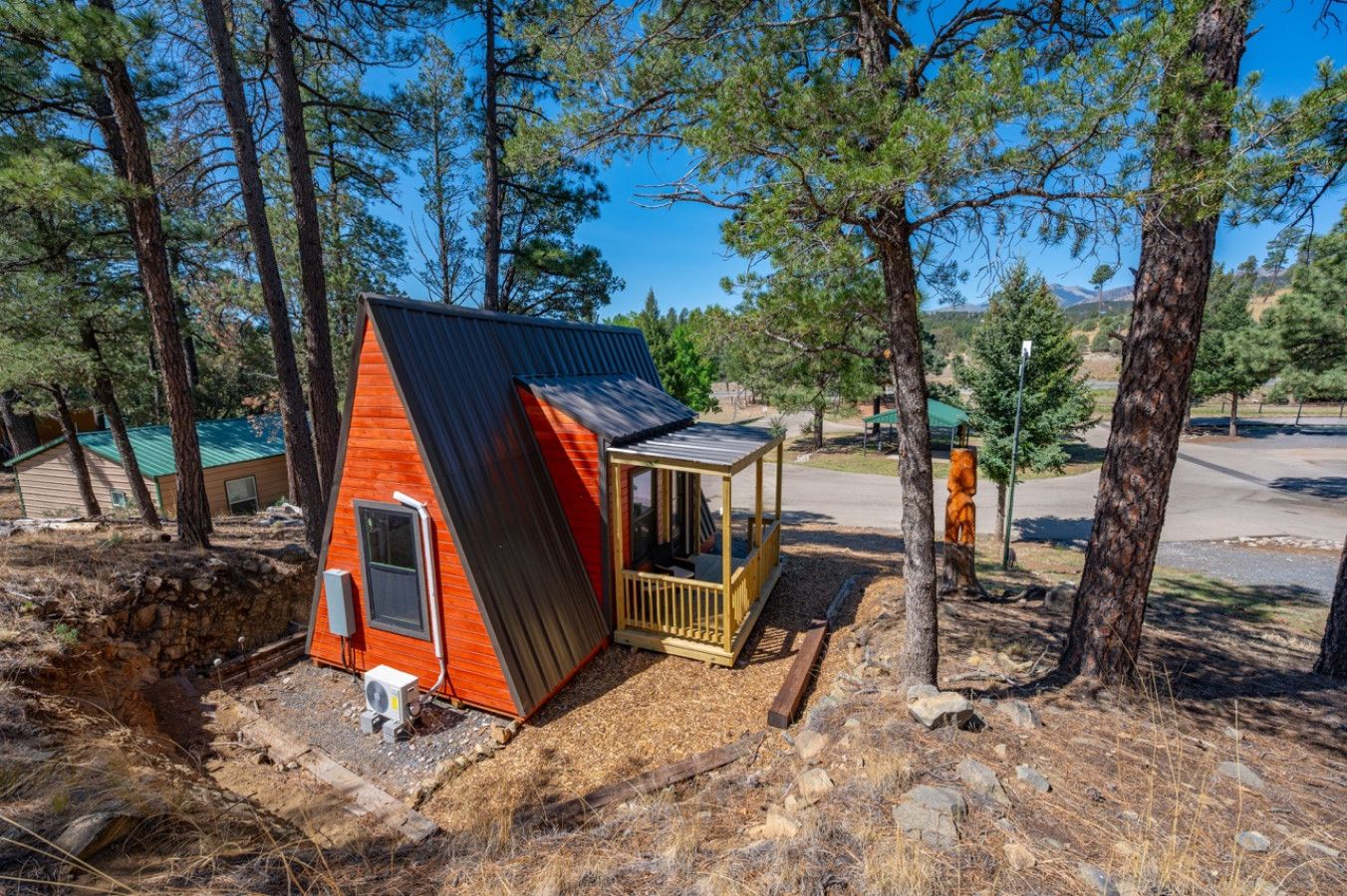 Une petite cabane avec un toit en pente, une véranda et des fondations en pierre.