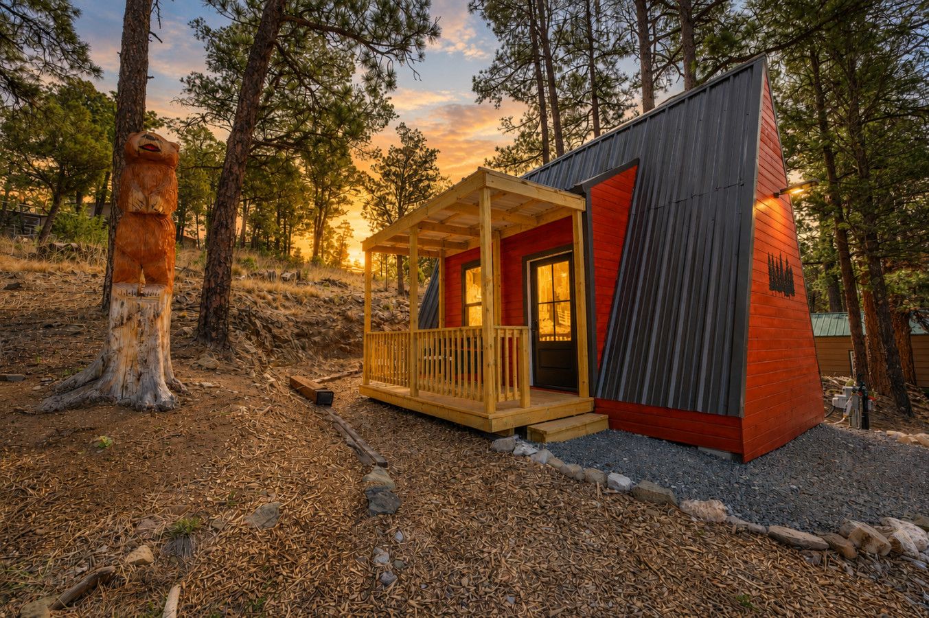 A cabin with a porch, a red exterior, and a wooden deck.