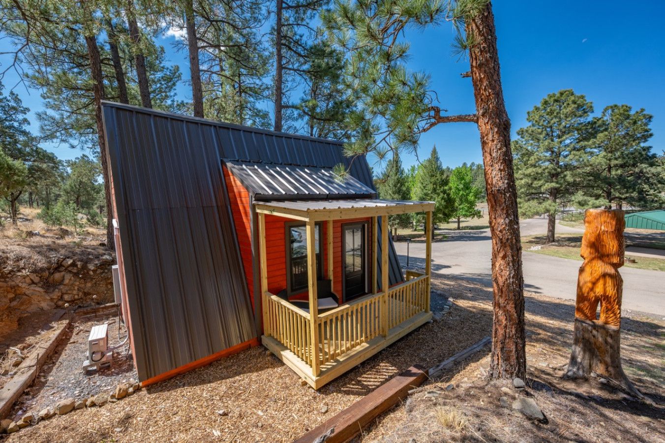 A small cabin with a porch, surrounded by trees.