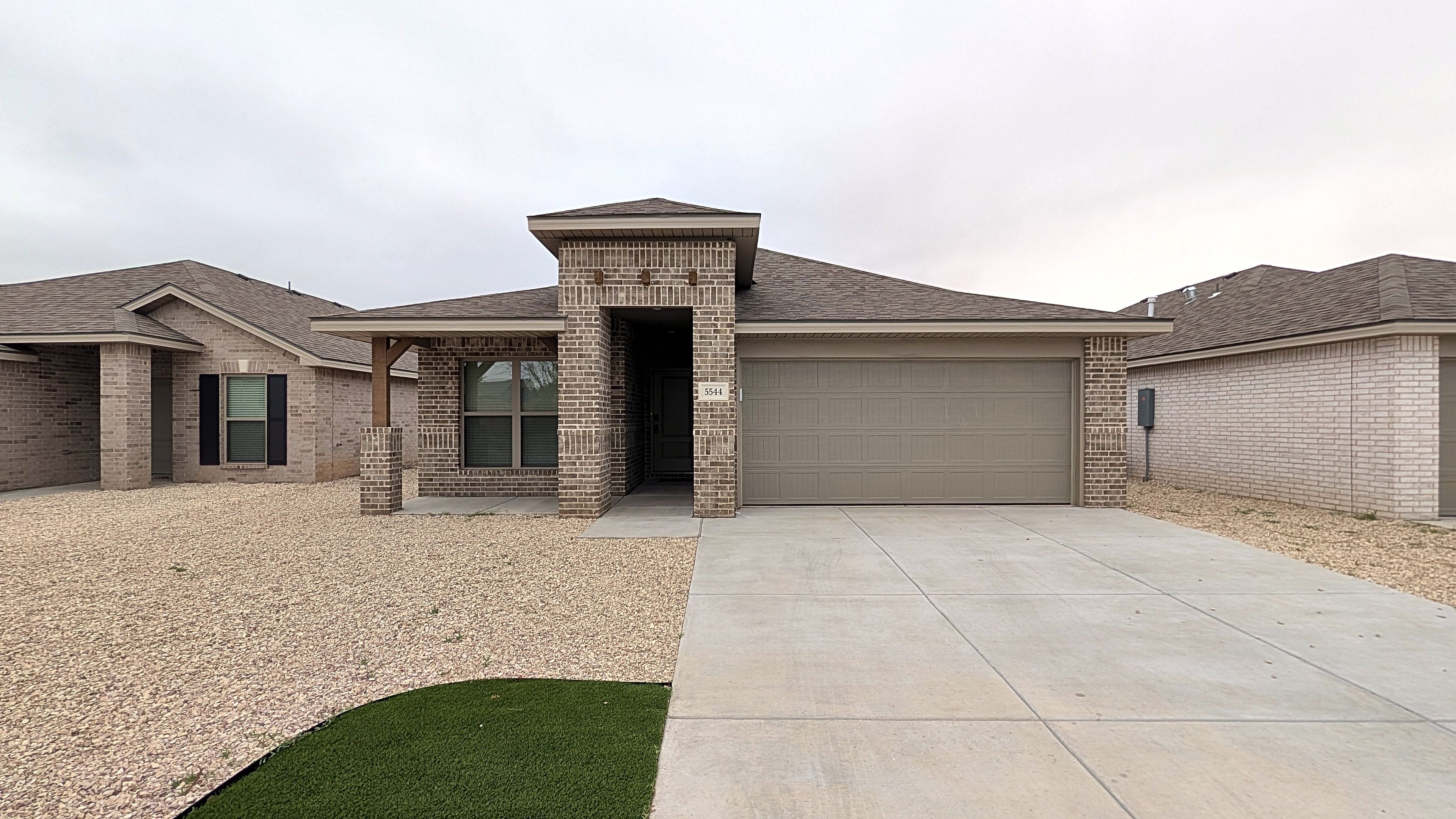 A residential house with a garage, a driveway, and a well-maintained lawn.