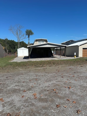 A building with a covered garage, a white shed, and a gravel driveway. - 3-bedroom cottage on the water in peaceful Hollywood with AC for relaxing stays (Hollywood)