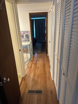 A hallway with wooden flooring, a metal vent, and a view of a balcony with a railing. - 3-bedroom cottage on the water in peaceful Hollywood with AC for relaxing stays (Hollywood)