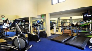 A gym with various cardio machines, including treadmills and elliptical trainers.