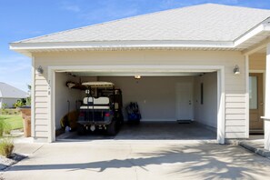 A garage with a vehicle inside, a door, and a small outdoor area with a trash bin. - Sweet 'N Salty (Port St. Joe)