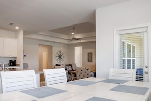 Ein Essbereich mit Tisch und Stühlen, ein Deckenventilator und eine Küche im Hintergrund.