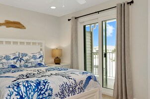 Un dormitorio con cama, mesita de noche, lámpara y vistas al exterior a través de una puerta corrediza.