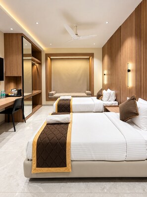 Habitación de hotel con dos camas, un escritorio, una silla, un televisor y un ventilador de techo.