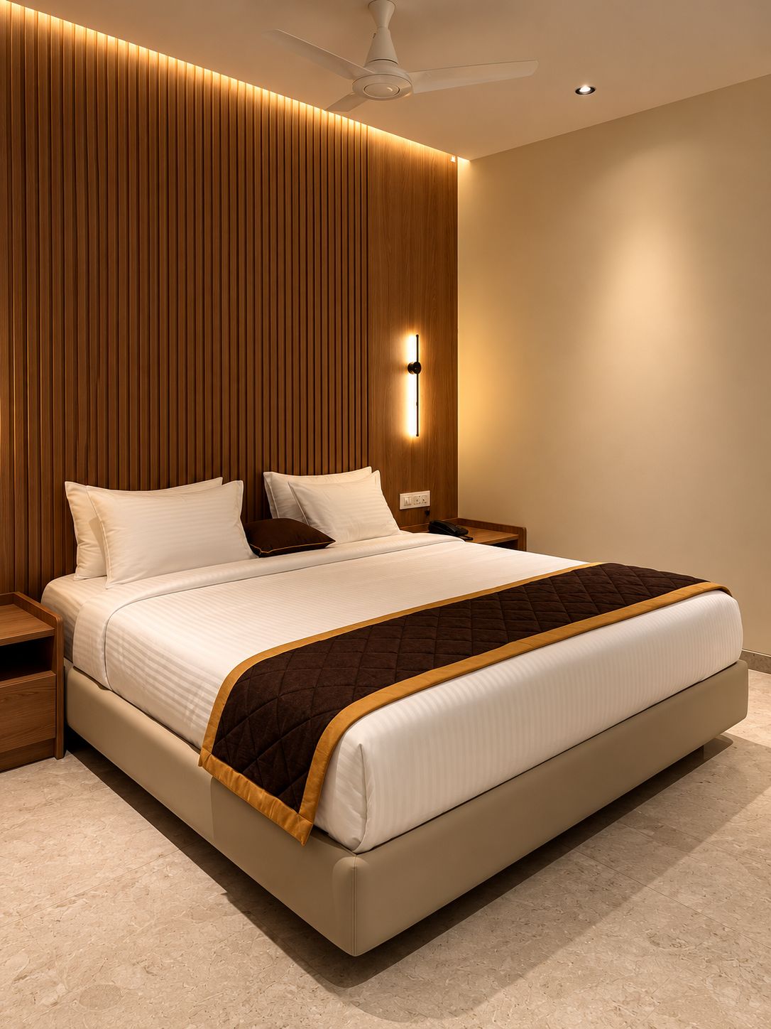 A modern bedroom with a large bed, a bedside table, a nightstand, a wall-mounted light, and a ceiling fan.