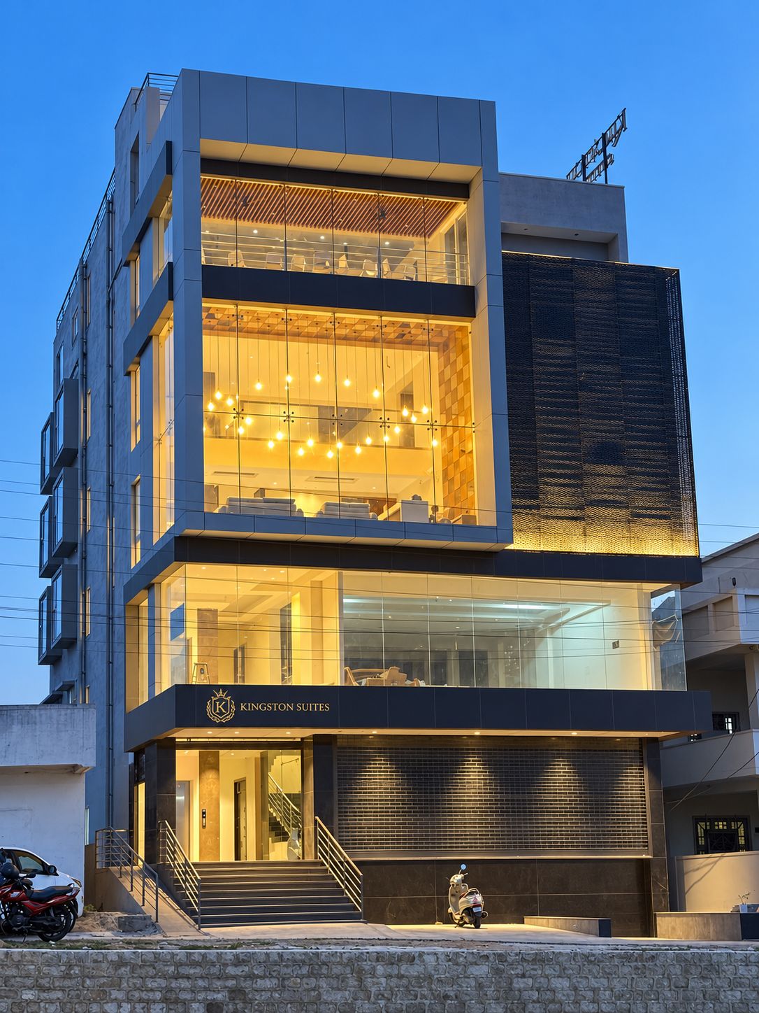 A modern building with a glass facade, a visible staircase, and a sign for 'Kingston Suites'.