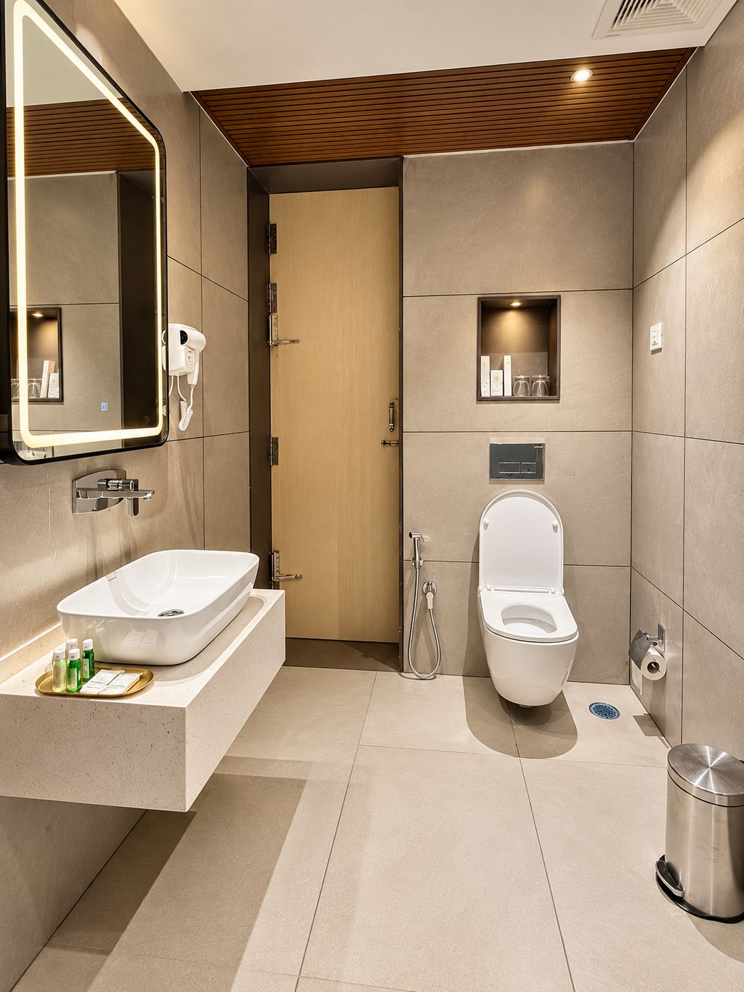 A modern bathroom with a large mirror, a sink, a toilet, and a shower.