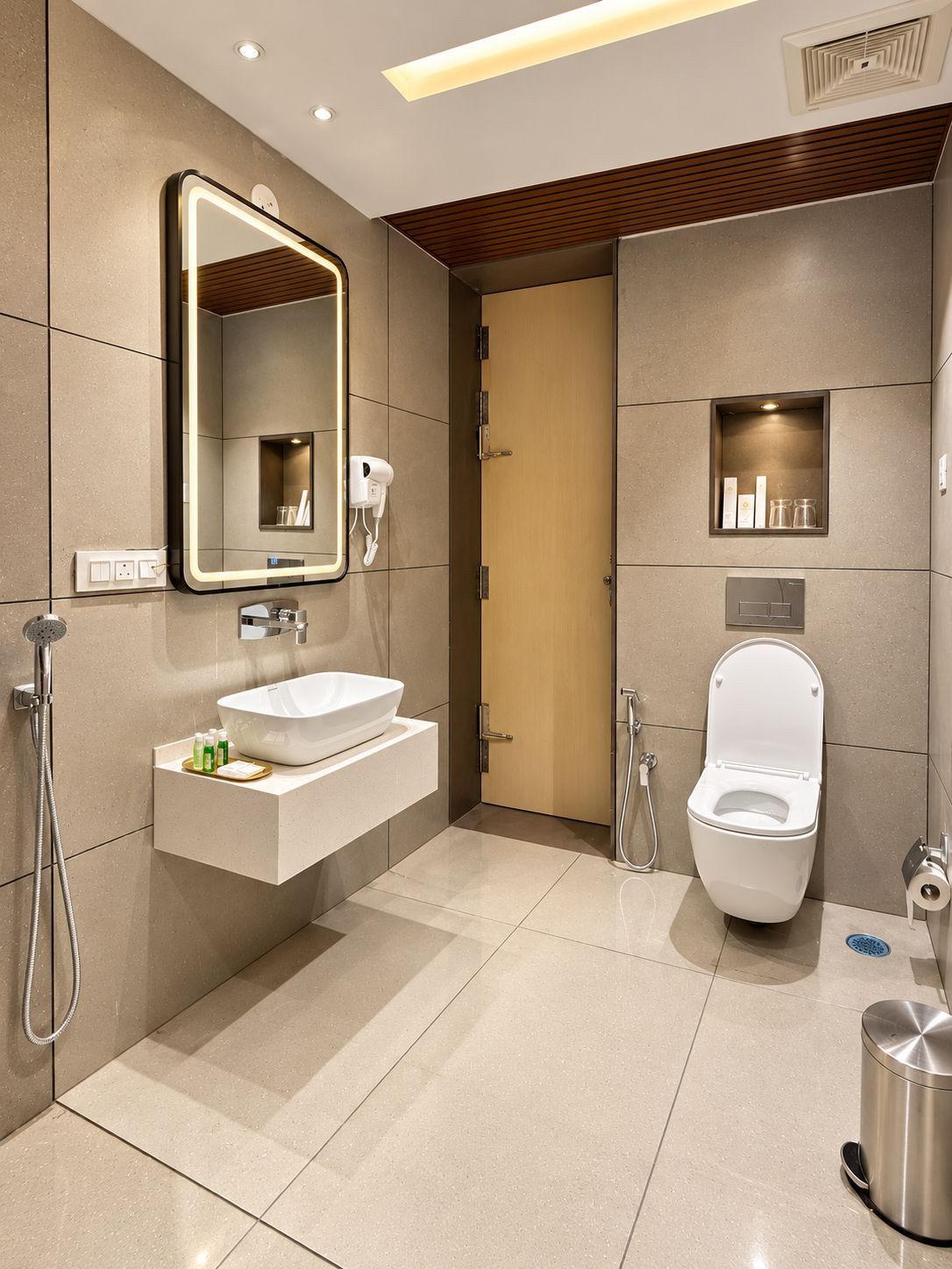 Une salle de bain moderne équipée d’un meuble-lavabo, d’un miroir, de toilettes et d’une douche.