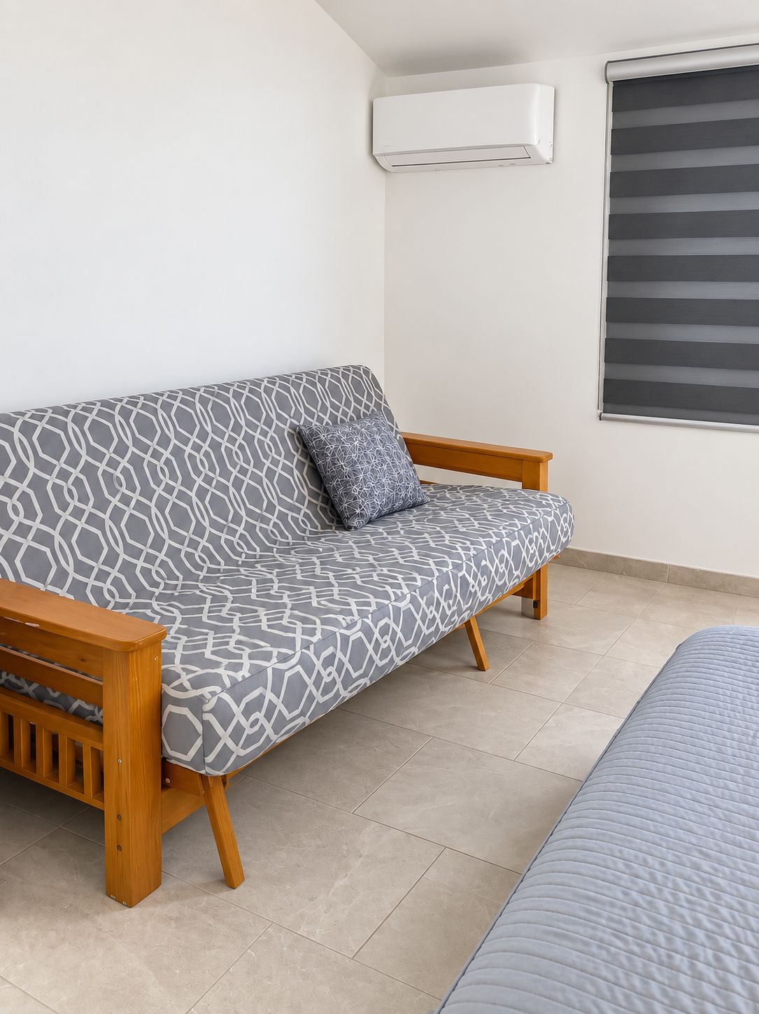 Een moderne kamer met een gestreept bankje, een houten zitting, een raam met jaloezieën en een airconditioning.