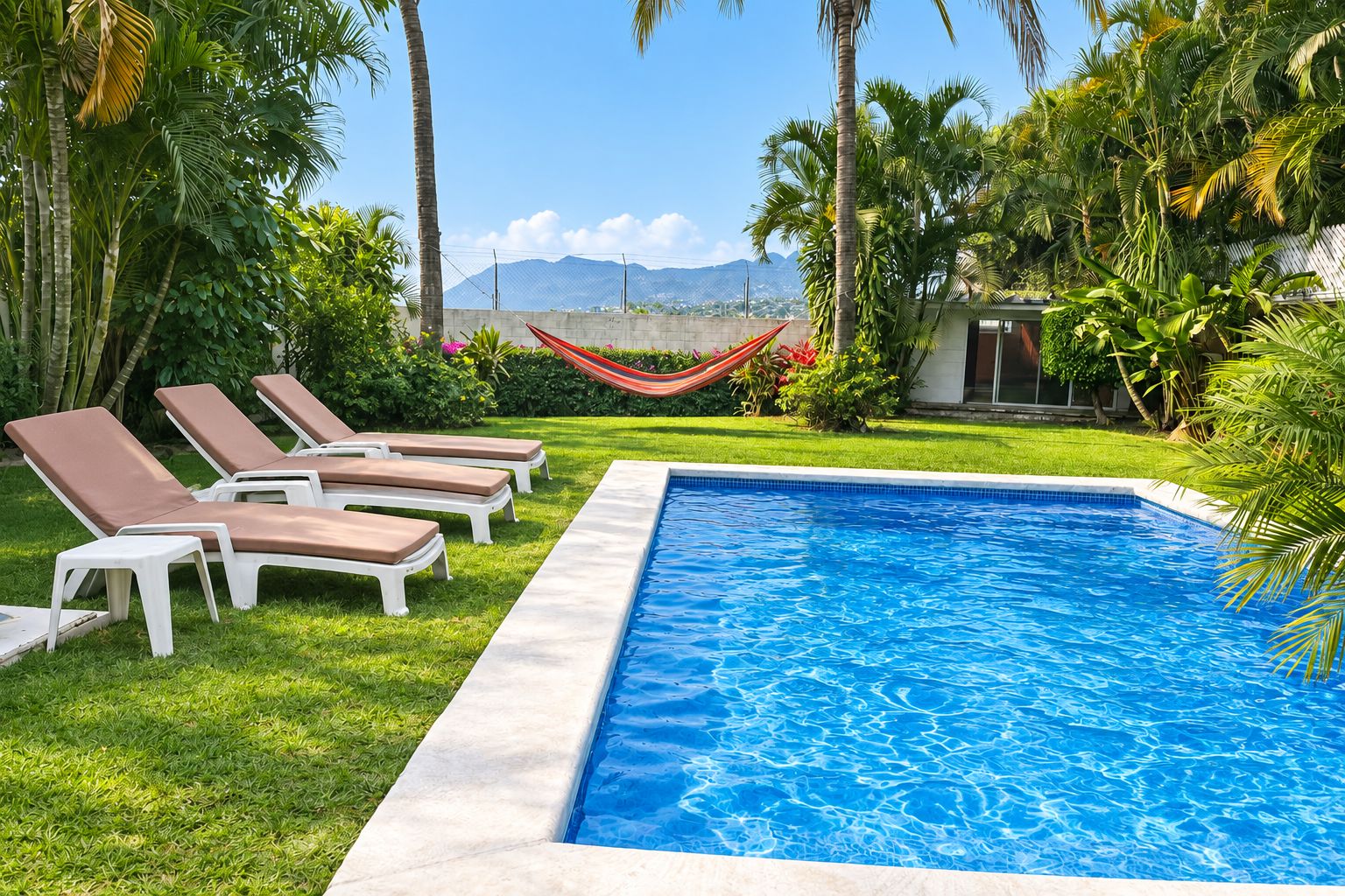 A swimming pool with lounge chairs and a hammock.