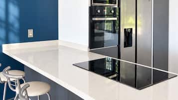 A modern kitchen with a central island, stainless steel appliances, and bar stools.