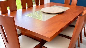 A rectangular wooden dining table with six chairs, each with a cushioned seat.
