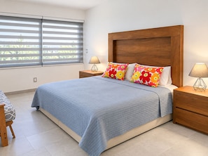Una camera da letto con un letto, due comodini, una sedia e una finestra con persiane.