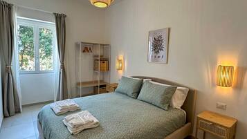 A bedroom with a bed, a bedside table, a lamp, a wardrobe, and a window with curtains.