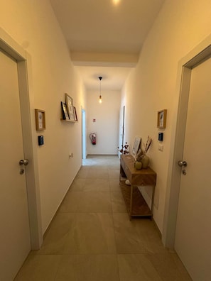 A hallway with a wooden bench, framed pictures, and a fire extinguisher. - defaultName (Olbia)