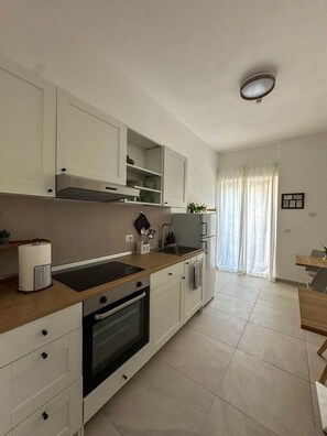 Une cuisine moderne avec des meubles blancs, un four encastré et un évier.