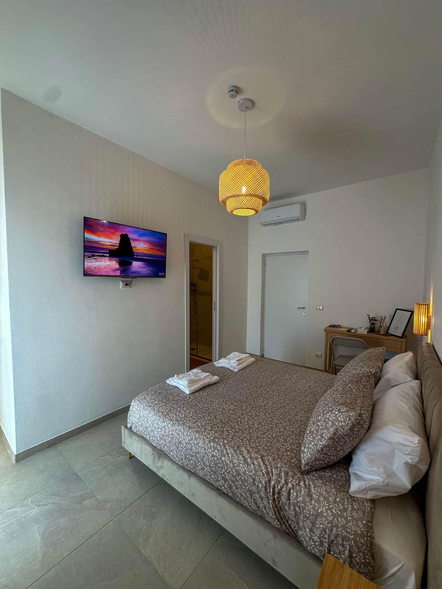 Una camera da letto con un letto, una televisione a parete, una porta e un condizionatore d'aria.