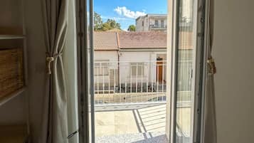 Ein Zimmer mit einer Schiebetür, die zu einem Außenbereich mit gefliestem Patio und Blick auf Gebäude führt.