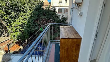 Ein schmaler Balkon mit einer Holzattrappe, einem Metallgeländer und einer Tür mit Fußmatte.