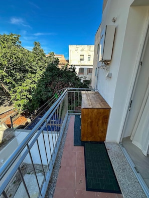 Ein schmaler Balkon mit einer Holzattrappe, einem Metallgeländer und einer Tür mit Fußmatte.