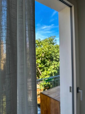 A view through a window with a mesh screen, a clear sky, and a green tree outside. - Lentischio - Camera King Deluxe Standard (Olbia)