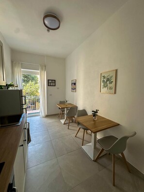 A modern kitchen with a built-in oven and a dining area with a wooden table and chairs. - Lentischio - Camera King Deluxe Standard (Olbia)