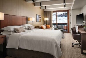 Ein Hotelzimmer mit einem großen Bett, einem Schreibtisch, einem Sessel und einem Fernseher.