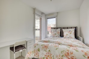 A bedroom with a bed, a desk, and a window. - Vrbo Property (Franconville)