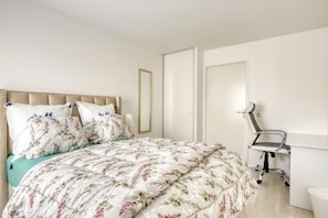 Een slaapkamer met een bed, een stoel, een spiegel en een deur.