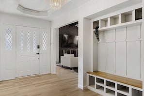 A modern interior with a wooden floor, white walls, a bench, and a TV mounted on a brick wall. - Spacious 4-bedroom house in enjoyable Plano (Plano)