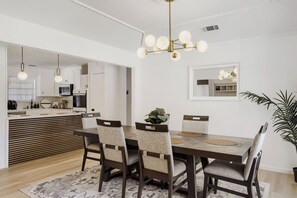 A modern dining area with a wooden table, upholstered chairs, and a hanging light fixture. - Spacious 4-bedroom house in enjoyable Plano (Plano)