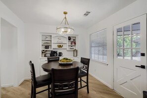 A dining area with a round table, chairs, a chandelier, and built-in shelving with various items. - Spacious 4-bedroom house in enjoyable Plano (Plano)