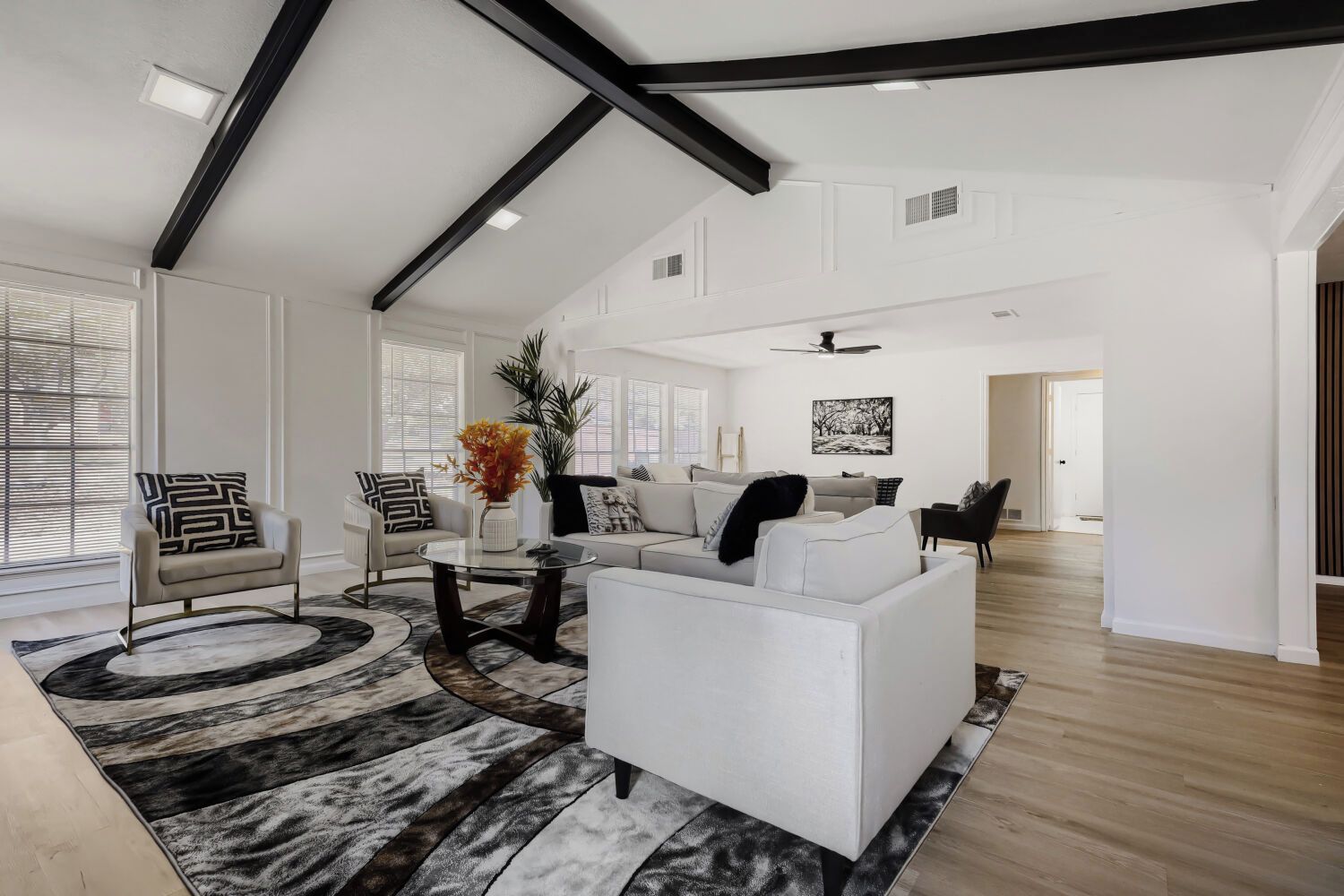 A spacious living room with a high ceiling, a fireplace, and a view of the outdoors.