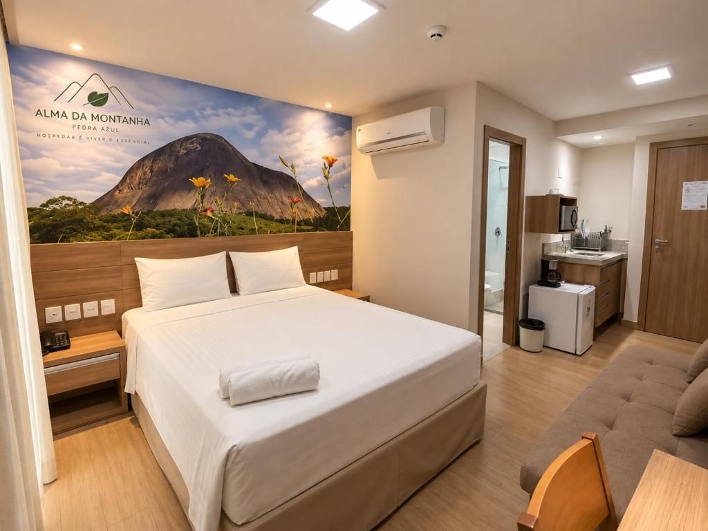 A hotel room with a bed, a sofa, a small kitchen area, and a bathroom.