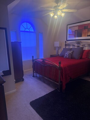 A bedroom with a bed, a ceiling fan, a window with blinds, and a wall-mounted lamp. - Tranquil 2-bedroom rooms for rent or short stay with AC in charming Cypress. (Cypress)