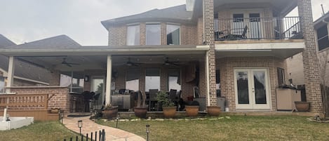 Une maison à deux étages dotée d’un patio couvert, d’une façade en briques et d’une cour clôturée.