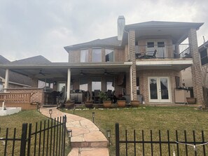 Una casa de dos plantas con porche cubierto, fachada de ladrillo y patio cercado.