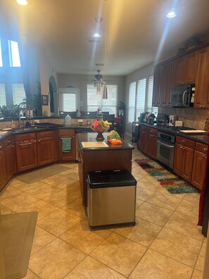 A spacious kitchen with a central island, wooden cabinets, a microwave, and a dishwasher. - Tranquil 2-bedroom rooms for rent or short stay with AC in charming Cypress. (Cypress)
