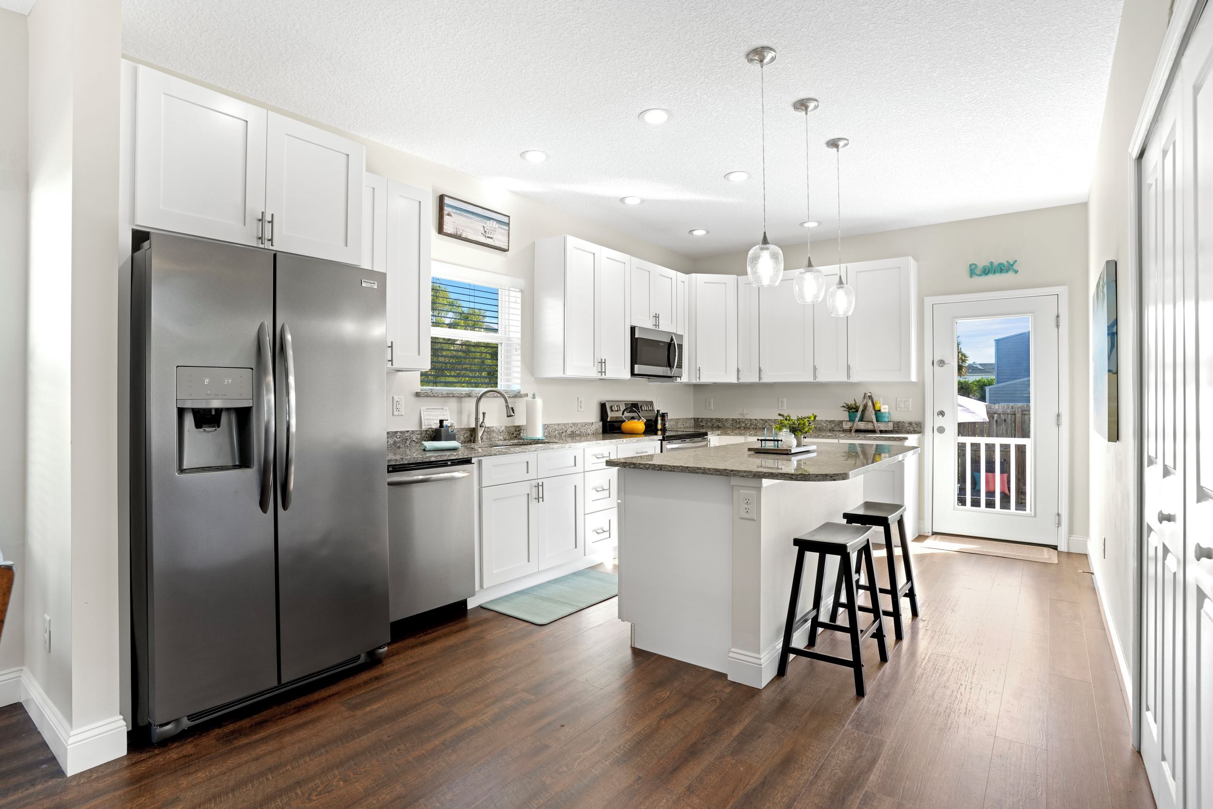 Cocina moderna con armarios blancos, electrodomésticos de acero inoxidable y una isla grande con taburetes.